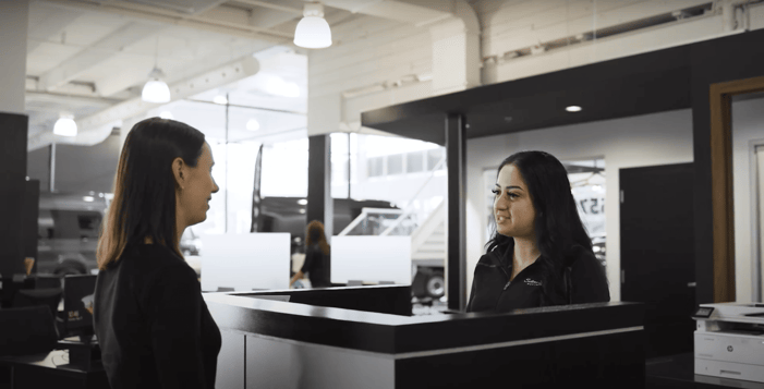 A lady greeting a client in a car dealership