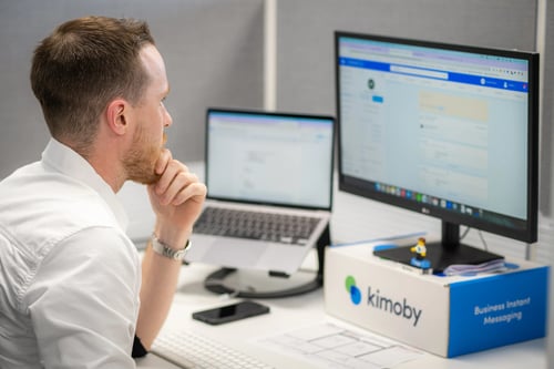A Kimoby employee at a desk working with two computer screens.