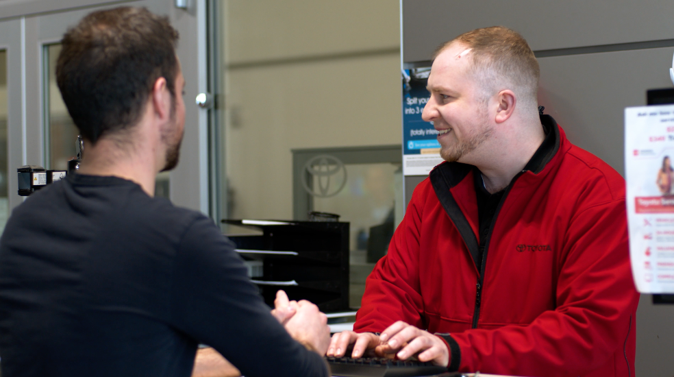 Dealership's customer at the service desk talking with a service advisor