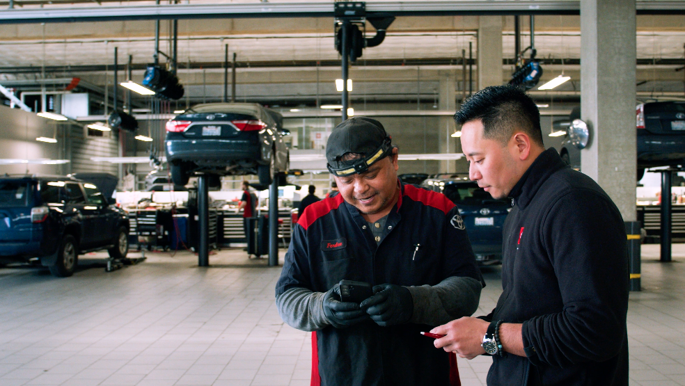 Two service workers looking at software on a phone, part of a service lane technology suite.
