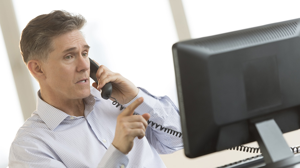 Someone looking at they computer screen while on the phone
